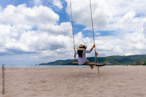 Phuket, Thailand Tropical beach paradise with beach swing with girl in white shirt. Women relax on swing under coconut palm tree at beautiful tropical beach White sand. summer holiday vacation concept