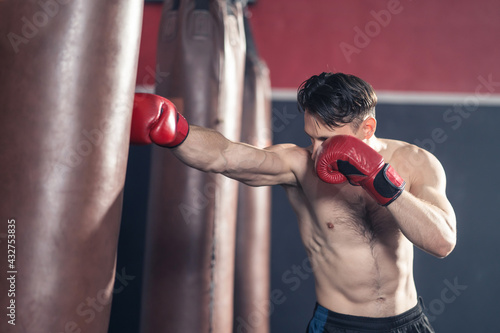Caucasian male athlete punching heavy bag for boxer training in gym. © Kawee