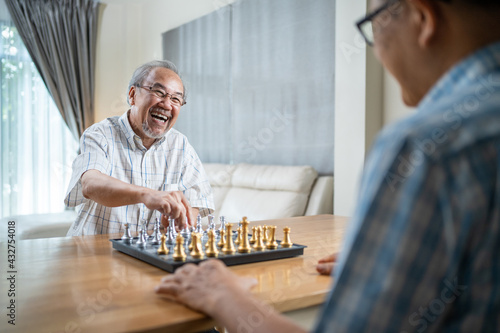 Asian old man enjoy playing chess together with friend in nursing home