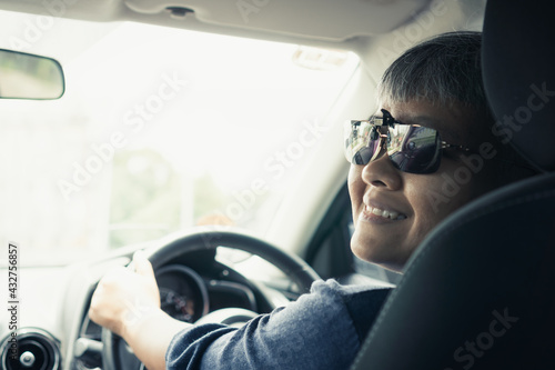 Happy on Trip or travel. Travel Asian smart seniors woman smiling driving car with sunglasses. Holding control steering wheel for trip on road. Transport on vehicle concept. Rear View © smolaw11