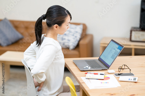 Foto 仕事中、腰痛に悩む女性