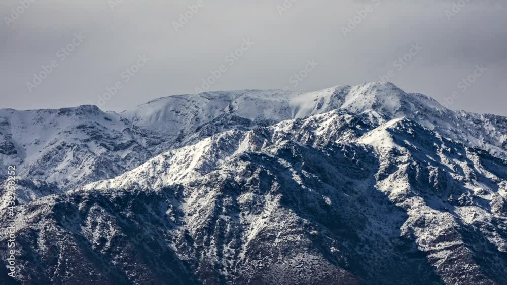 Andes mountains during winter time. Snowcapped summits and strong winds moving the clouds at Cerro La Cruz in Central Andes mountain range. An amazing rugged landscape