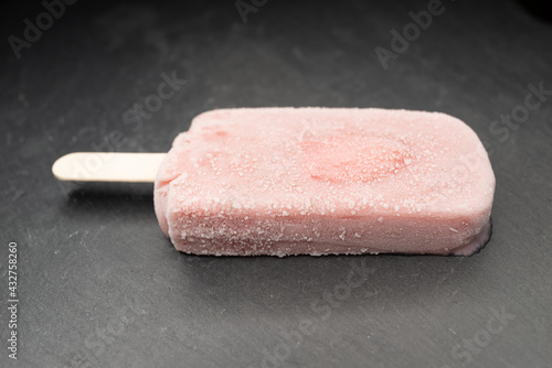 angle view fresh milk flavor popsicle with strawberry slice on dark