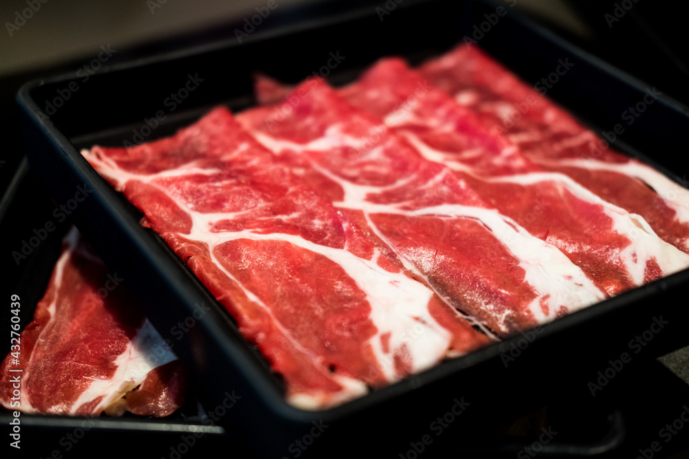 Thin sliced beef for Shabu hot pot on black tray. Stock Photo Adobe Stock