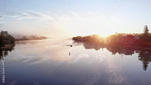 Low angle sun emphasizes the wake left by small boat in a wide river(aerial). photo