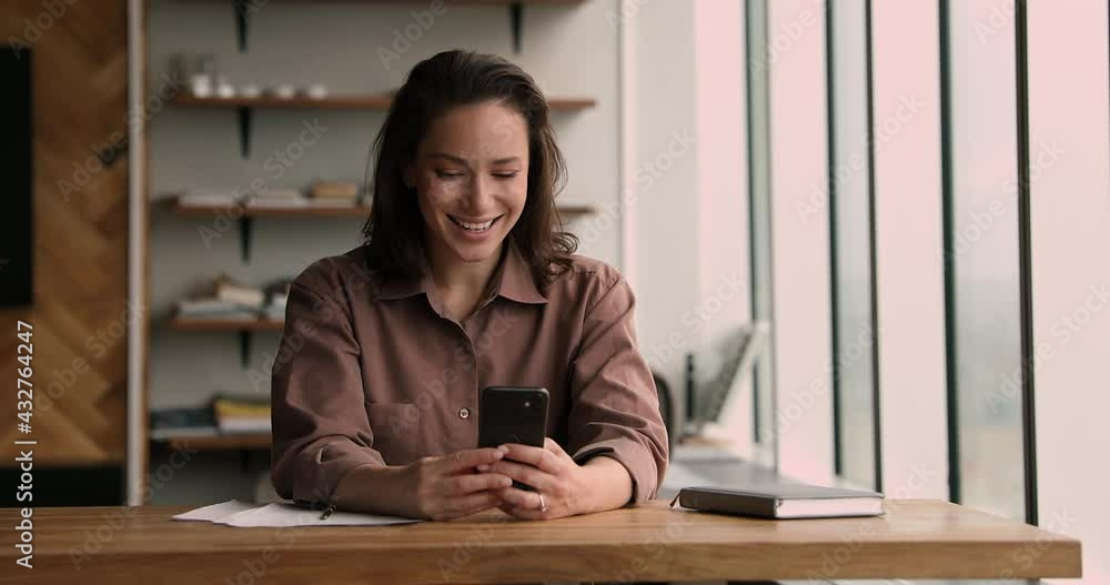 Young Caucasian female employee look on cellphone screen smiling enjoy break at workplace using modern tech, online fun, e-date application usage, check email and social networks, technology concept Young Caucasian female employee look on cellphone screen smiling enjoy break at workplace using modern tech, online fun, e-date application usage, check email and social networks, technology concept