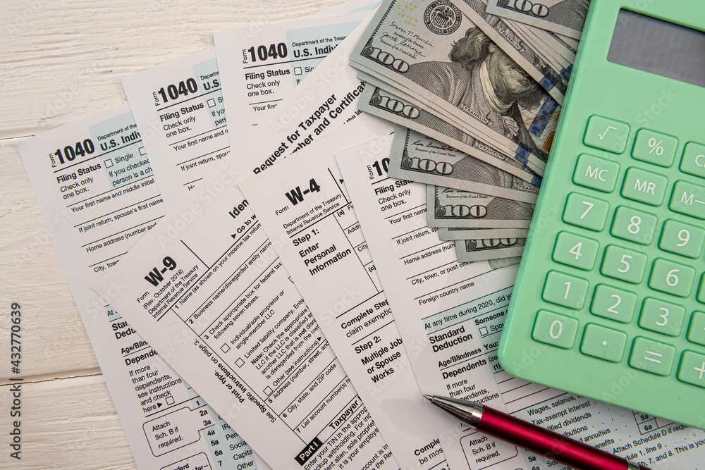 US individual 1040 form with dollar bills calculator and pen paperwork US individual 1040 form with dollar bills calculator and pen paperwork