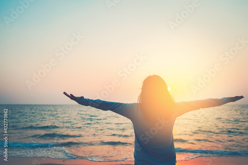 Copy space of woman rise hand up on sunset sky at beach and island background. © tonktiti