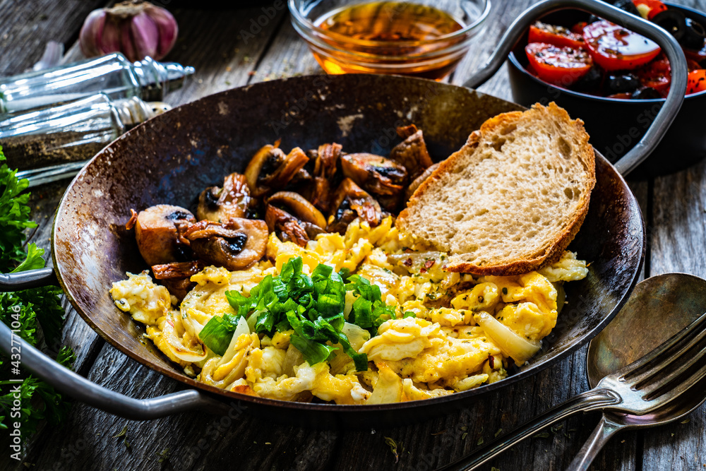 Delicious breakfast - scrambled eggs with fried white mushrooms and vegetable served on frying pan on wooden table
Delicious breakfast - scrambled eggs with fried white mushrooms and vegetable served on frying pan on wooden table