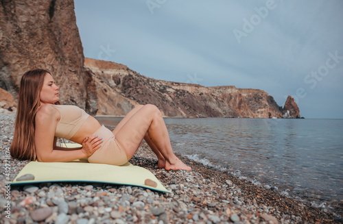 Young woman in beige sportswear with long hair practicing stretc photo