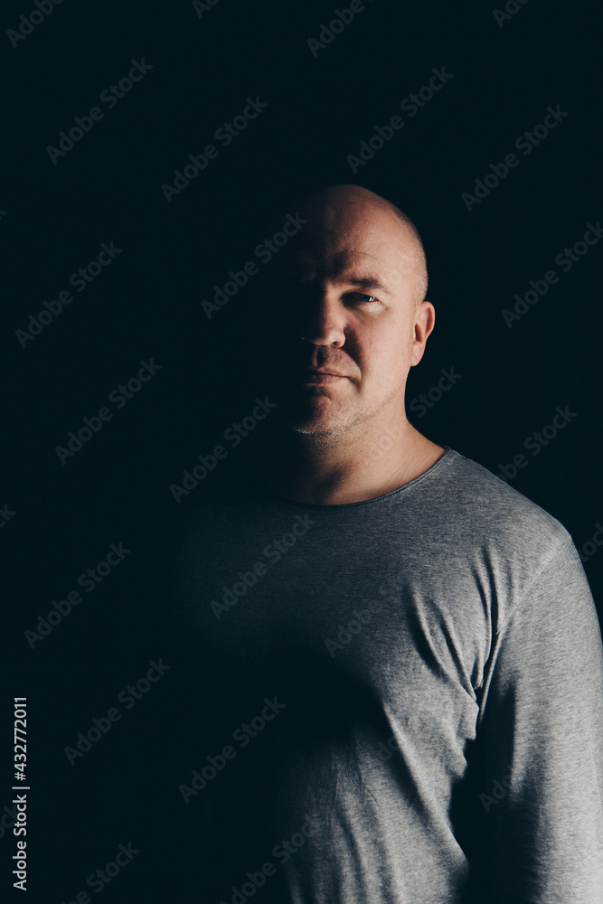 bald handsome man in gray clothes on black background bald handsome man in gray clothes on black background