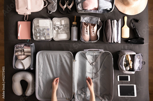 Top view woman hands getting ready to travel vacation packing suitcase use konmari method