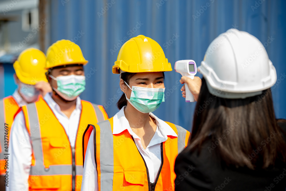 The staff measures the temperature of workers before entering work. At the port of transport Concept of COVID-19 prevention. The staff measures the temperature of workers before entering work. At the port of transport Concept of COVID-19 prevention.