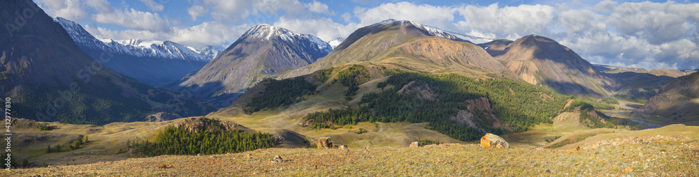 Fototapeta premium Panoramic mountain view, morning light. Steep slopes, snowy peaks and forest. Traveling in the mountains, trekking.