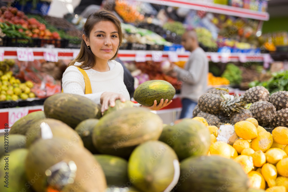 Latin woman choosing sweet melon and man near coosing other products