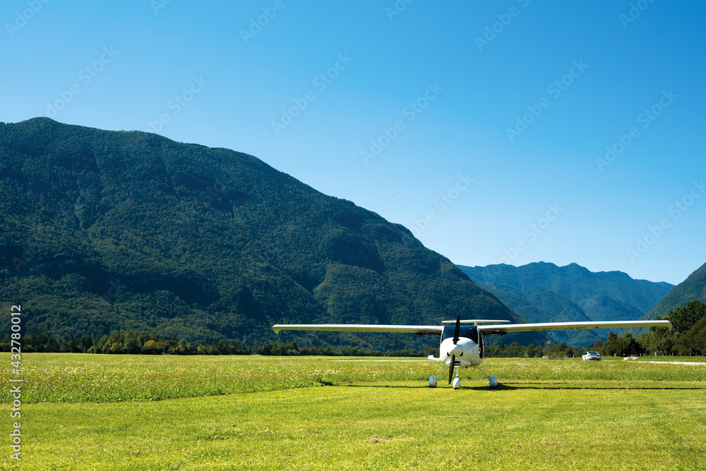 Small plane landed on green airfield in alps
