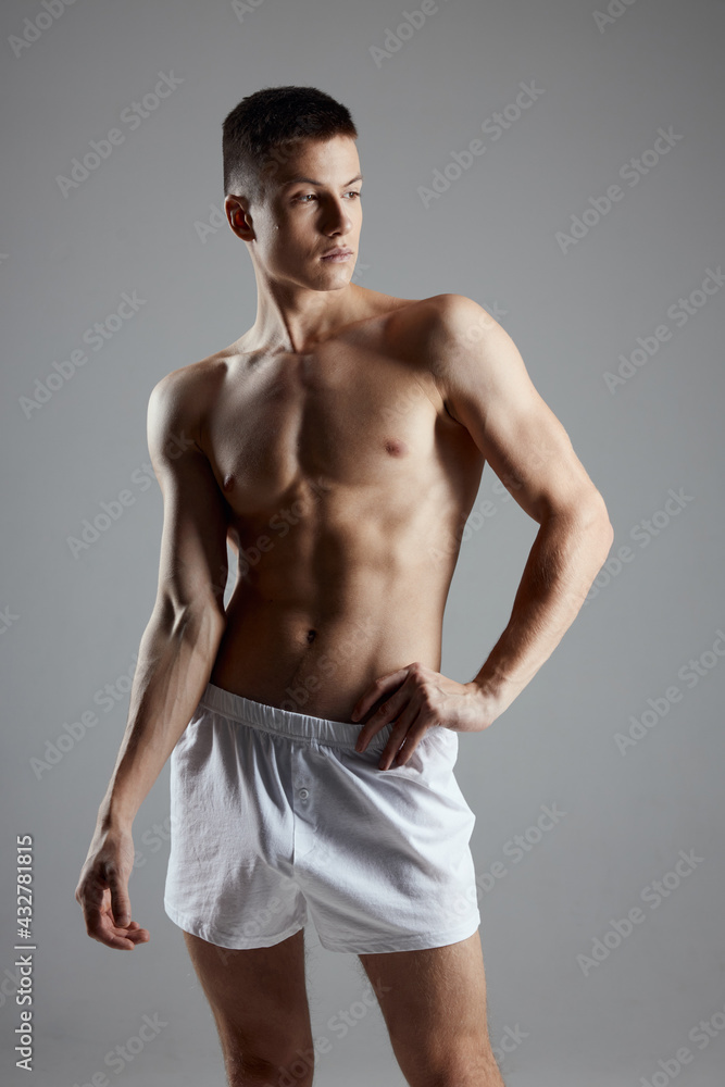 man bodybuilder in white shorts gesturing with hands on gray background sport fitness model