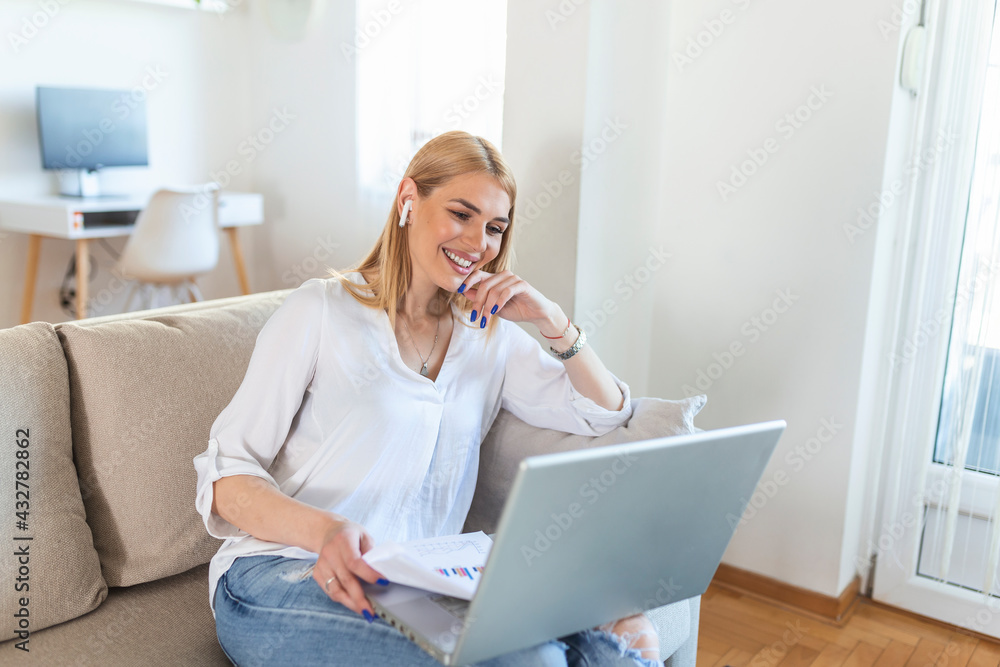 Smiling young woman using laptop at home, looking at screen, chatting, wearing wireless headset having video conference . business trainer tutoring by webcam, online training, e-coaching concept Smiling young woman using laptop at home, looking at screen, chatting, wearing wireless headset having video conference . business trainer tutoring by webcam, online training, e-coaching concept
