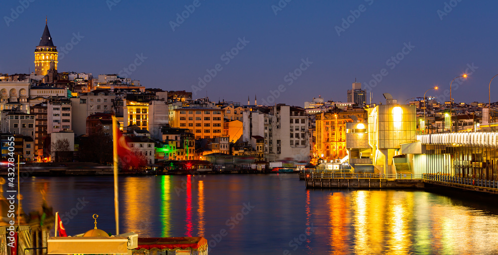 Scenic view of lighted Karakoy quarter and Galata Tower from Golden Horn Bay in winter twilight, Istanbul, Turkey