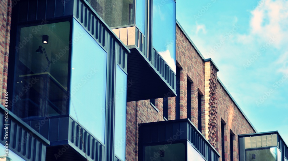 Modern brick and glass facade of the office building.  A contrasting combination of sky and brick texture on a building. Architectural facade of a red brick building. Retro filter.