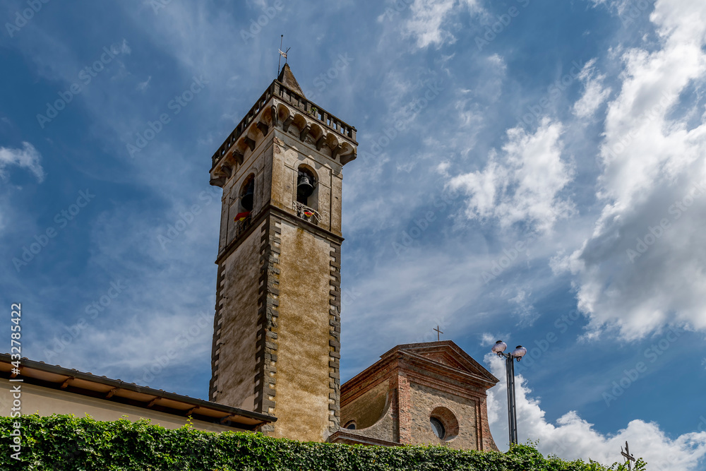 The bell tower and part of the facade of the Santa Croce church in the historic center of Vinci, Florence, Italy, against a dramatic sky