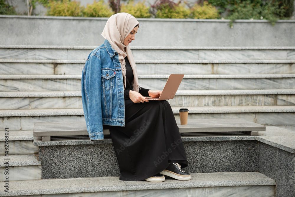 Naklejka premium modern stylish muslim woman in hijab in city street