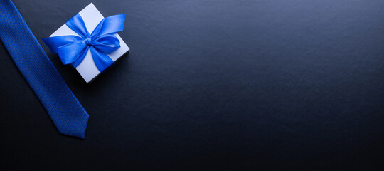 Gift father day. Blue bowtie or tie, white box with bow ribbon on dark background. Happy loving family and Fathers Day concept.