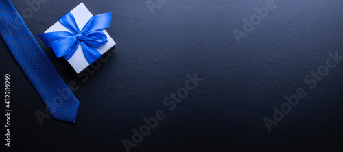 Gift father day. Blue bowtie or tie  white box with bow ribbon on dark background. Happy loving family and Fathers Day concept.