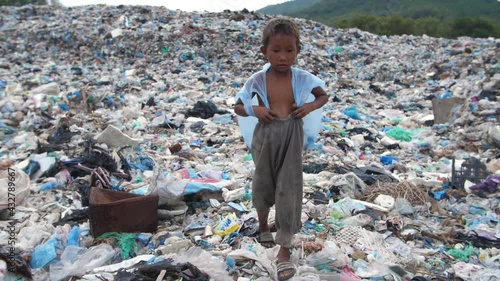 Poor Boy Walking On Garbage Dump
