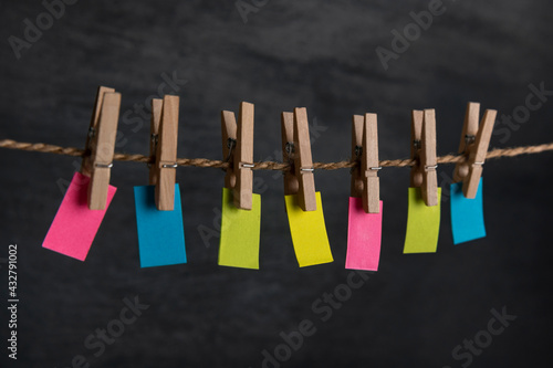 Small varicolored paper hang with clothespins on rope. Copy space. Place for your text. Note, reminder. © somemeans