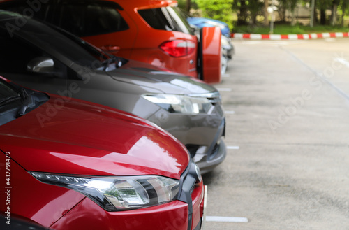 Closeup of front side of red car with other cars parking in outdoor parking area.