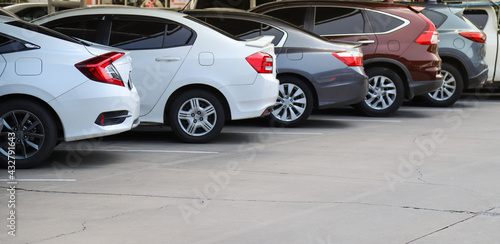 Closeup of rear, back side of white car with other cars parking in indoor parking area.