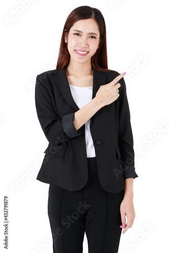 Asian adorable business woman with hair tied wearing casual black suit, happily smiling, pointing at blank copy space for advertisement, isolated white background cutout.