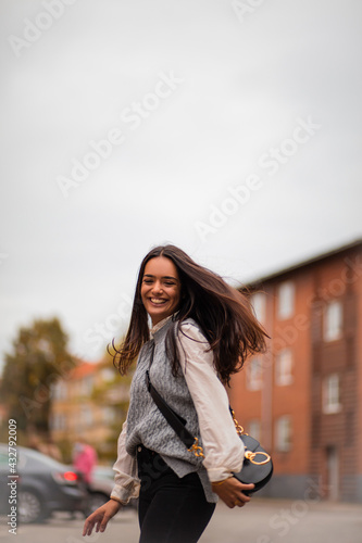 Smiling young woman dancing on street.