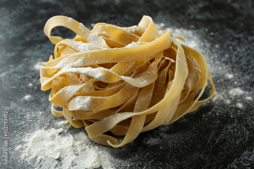 Uncooked pasta with flour on black smokey background