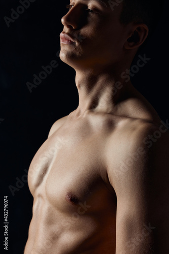 side view of sexy bodybuilder with naked torso on black background portrait