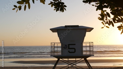Lifeguard watch tower, sunny sunset beach, Oceanside USA. Rescue station, waterfront watchtower hut and tree leaves, pacific ocean coast atmosphere. California summertime aesthetic, Los Angeles vibes.