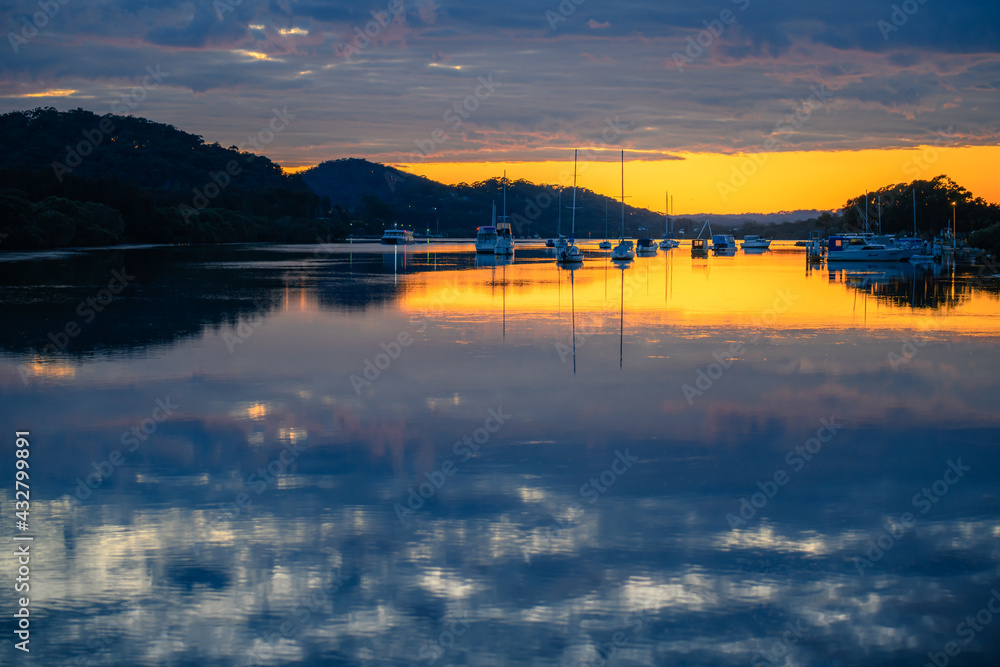 Dawn waterscape with clouds, reflections and boats in the channel