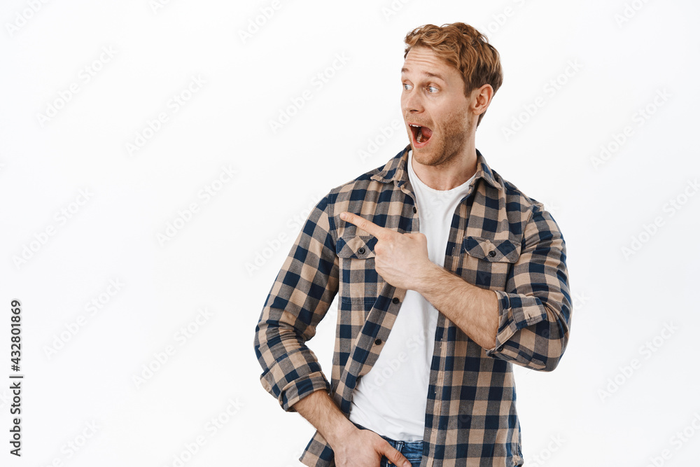 Wow look at that. Excited happy guy drop jaw from amazement, pointing finger aside left, looking at promo offer with joyful expression, found something cool, standing over white background Wow look at that. Excited happy guy drop jaw from amazement, pointing finger aside left, looking at promo offer with joyful expression, found something cool, standing over white background