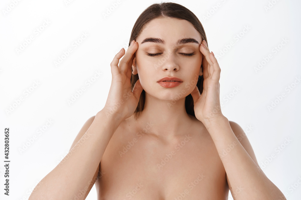 Spa, beauty and cosmetology. Woman touching temples, fingers on healthy clean natural face, eyes closed, facial massage with argan oil, skincare cosmetics, applying cream, white background Spa, beauty and cosmetology. Woman touching temples, fingers on healthy clean natural face, eyes closed, facial massage with argan oil, skincare cosmetics, applying cream, white background