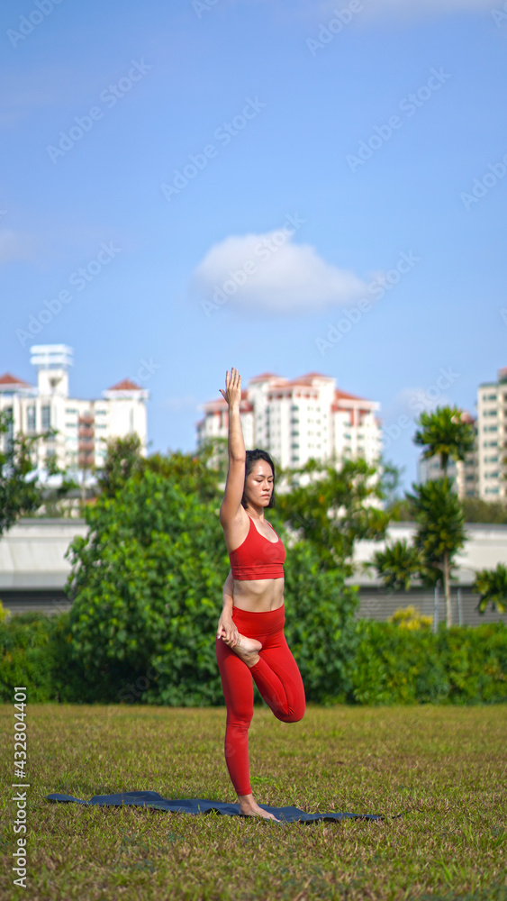 asian chinese female lady yogi practise yoga stretches poses in the park in beautiful weather