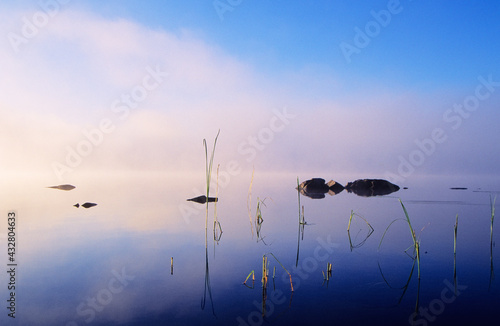 Mist over calm lake water surface. Early morning view.
