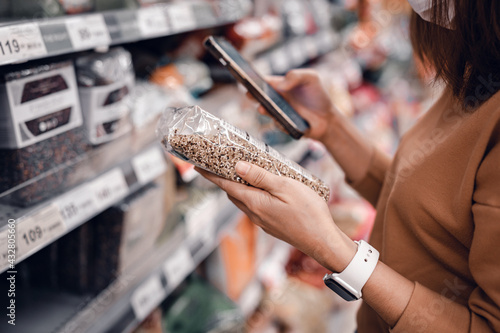 Fotografía Closeup - Woman shopping in supermarket and reading product information