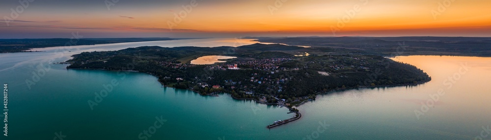 Tihany, Hungary - Aerial panoramic view of Tihany Peninsula with Benedictine Monastery of Tihany (Tihanyi Apatsag), Tihany Port, Inner Lake and beautiful golden summer sky at sunset over Lake Balaton