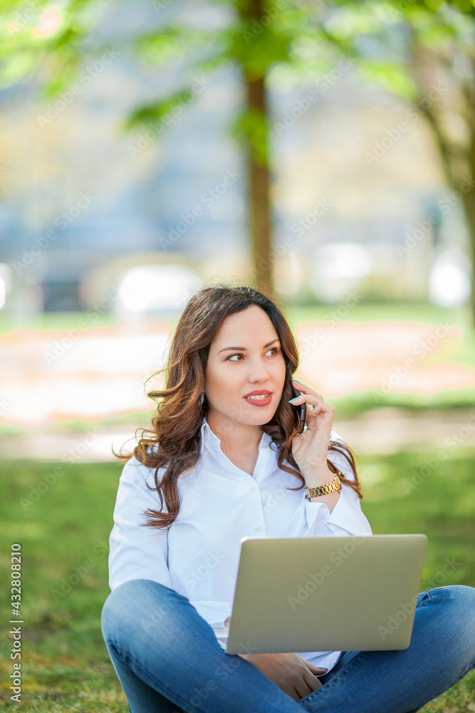 Young happy woman works at a laptop in nature. Quarantine. Freelancer. Young happy woman works at a laptop in nature. Quarantine. Freelancer.