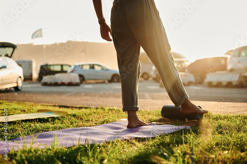 cropped body of unrecognizable girl ready for a stretching session at sunset with moody light