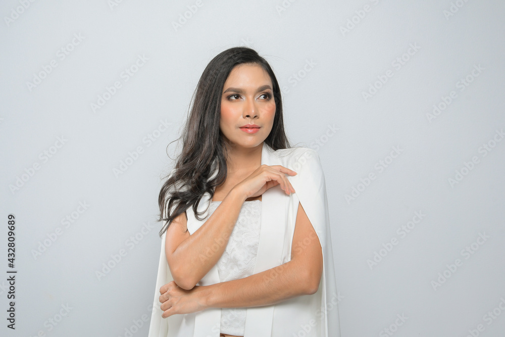 High fashion shot of young long black hair woman in white suit at studio shoot isolated on gray background. High fashion shot of young long black hair woman in white suit at studio shoot isolated on gray background.