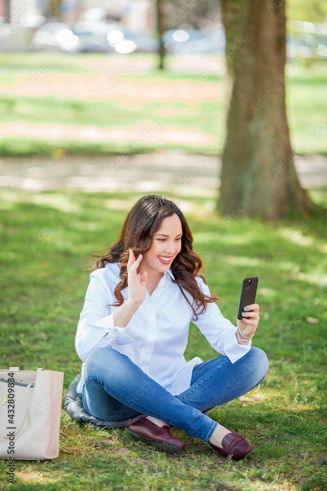 Young happy woman speaks by video call in nature. Quarantine. Young happy woman speaks by video call in nature. Quarantine.