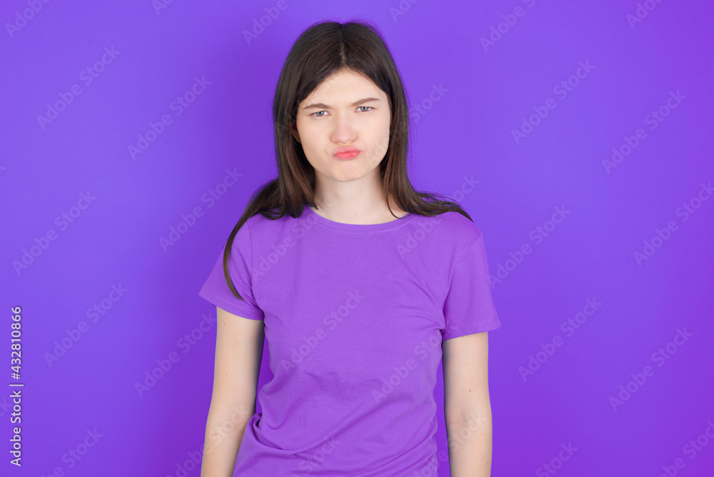 Offended dissatisfied young beautiful Caucasian girl wearing purple T-shirt over purple background with moody displeased expression at camera being disappointed by something Offended dissatisfied young beautiful Caucasian girl wearing purple T-shirt over purple background with moody displeased expression at camera being disappointed by something