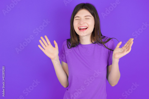 Crazy outraged young beautiful Caucasian girl wearing purple T-shirt over purple background screams loudly and gestures angrily yells furiously. Negative human emotions feelings concept